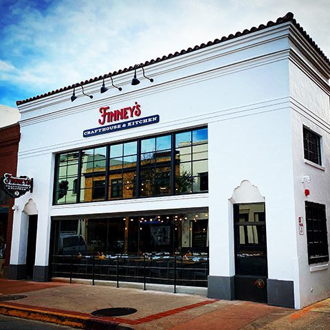 Front view of Finney's Craft House & Kitchen, a white building with large windows and the restaurant's signage prominently displayed.